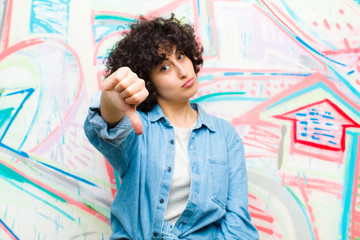 young pretty afro woman feeling cross, angry, annoyed, disappointed or displeased, showing thumbs...