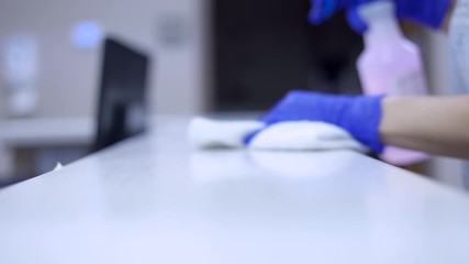 Janitor cleaning medical counter in office with commercial sanitizing cleaner with blue surgical gloves with shallow depth of field