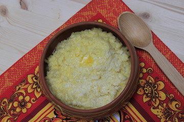 Milk porridge in a clay bowl stands on a red towel.