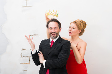 Positive man in formal suit being pleased with a crown above his head