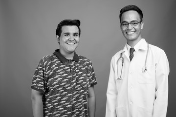 Young multi-ethnic man and young Indian man doctor against gray background