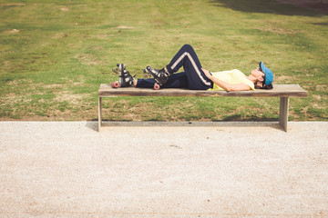 Woman with roller skates resting relaxed on a park bench