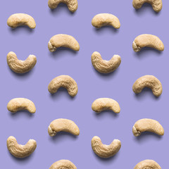 Fresh healthy tasty nutritious cashew on light violet background. Top view. Flat layout. Seamless...