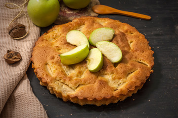 Charlotte apple pie on a black wooden table with slices of green apples
