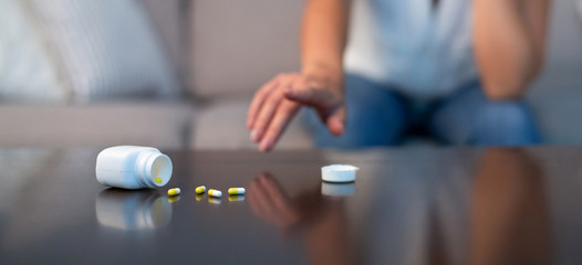 Fototapeta premium Unrecognizable Girl Reaching For Sleeping Pills Sitting On Couch Indoor