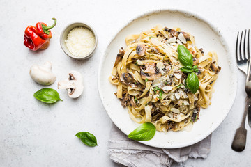 Tagliatelle pasta with mushrooms, cheese and Basil Leaf on white plate, top view