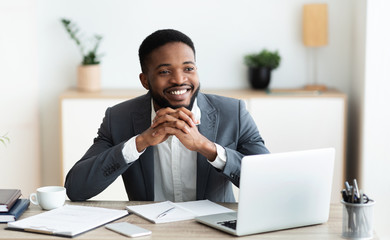 Smiling black businessman daydreaming at workplace in office