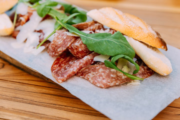 Close-up sliced salami served with bread, cheese and rocket.  