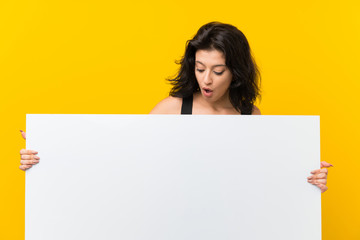Young woman over isolated yellow background holding an empty white placard for insert a concept