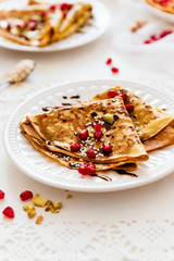 Thin Crepes with melted chocolate, sesame seeds, pomegranate and almonds. Tasty thin pancakes
