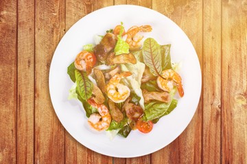 Spaghetti with shrimps, tomatoes and chopped parsley on wooden desk