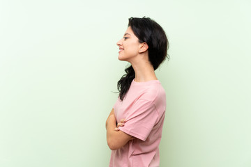 Obraz premium Young woman over isolated green background in lateral position