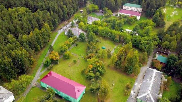 Recreation center in forest near lake. Stock footage. Top view of beautiful tourist base in picturesque area with lake. Rest at camp site surrounded by nature