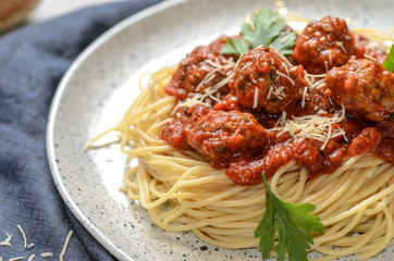 The homemade italian pasta or spaghetti with meatball , cheese and tomato sauce placed in a white dish with on dark blue tablecloth on the table..