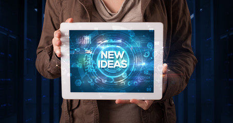Young business person working on tablet and shows the inscription: NEW IDEAS, business concept