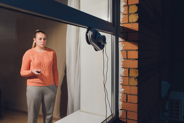 Vacuum cleaner robot cleaning window in high building outdoor. young woman controls the remote