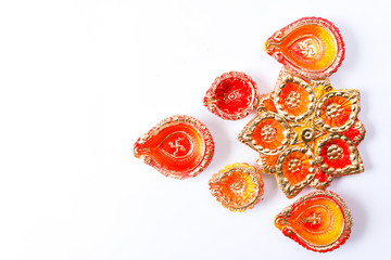 Happy Diwali, Colorful design of Clay Diya lamps lit during Dipavali festival on white background