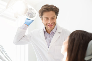 Cheerful young dentist greeting his female patient