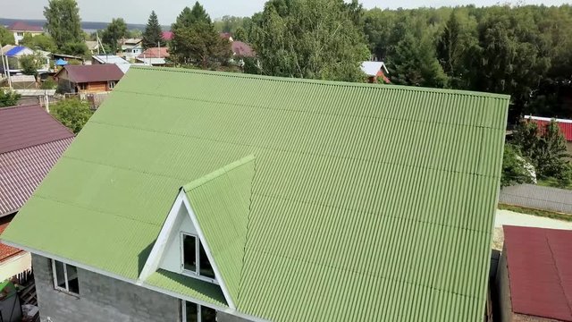 Covering green roof of village house. Stock footage. Top view of roof profiled green roof of house. New green roof of village house in summer