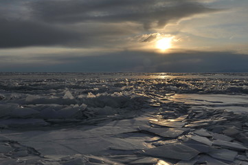 Lake Baikal in the winter. Crystal clear ice covers the lake. Coastal stones and rocks are covered with a layer of ice.