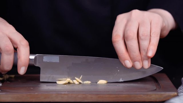 Step by step. Dicing organic garlic on wood cutting board.