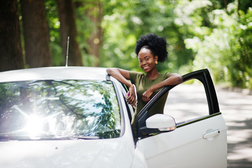 African american woman posed against white car in forest road.