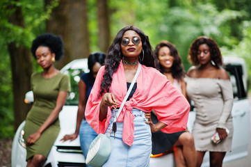 Fototapeta premium Group of five happy african american girls posed against car, one of them show keys.
