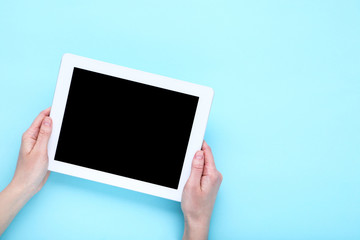 Tablet computer in female hands on blue background