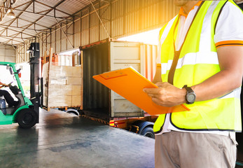 freight industry warehouse logistics transport, worker in uniform hand holding clipboard inspecting checklist load cargo shipment with a trucks