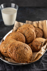 Chocolate chip cookies with milk on black table. Copy space.