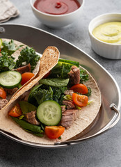 Two mexican pork carnitas tacos with sauces and vegetables.