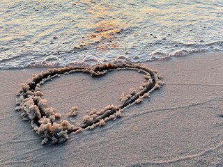 Drawing hearts on the sandy shore. Sign drawn on the sand, closeup. Concept: Declaration of Love