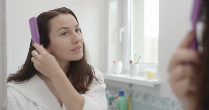 Woman is Brushing Hair after Shower with Hair Brush in Bathroom Shot on Red Epic