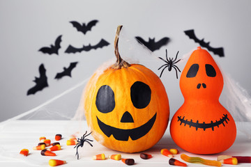 Halloween pumpkins with candies and paper bats on grey background