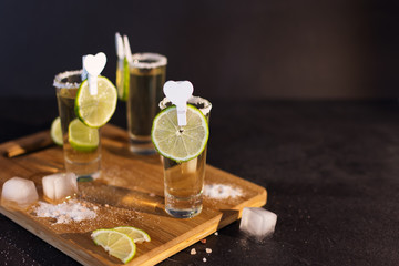 Shot glasses of gold tequila with a rim of salt, and lime slices.