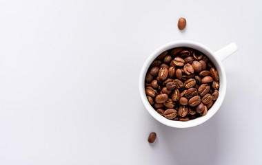 Roasted coffee beans in a white cup on a grey background, top view, copy space. Minimal style.