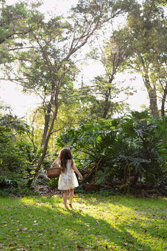 A little girl collecting easter eggs and climbing a tree