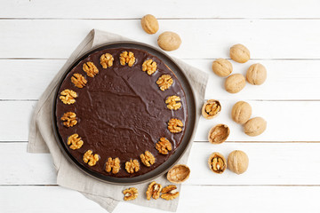 Homemade Walnut Cake with Chocolate Icing on white wooden table. Top view.