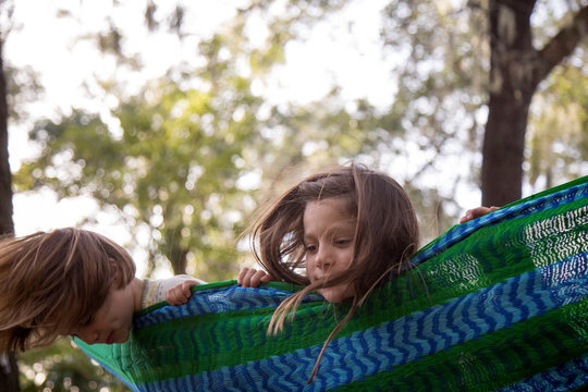 Two little girls swinging in a hammock looking over the side