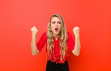 young blonde woman celebrating an unbelievable success like a winner, looking excited and happy...