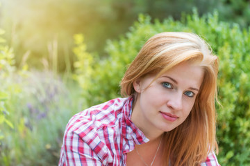 Pensive long hair young woman is looking at the camera outdoors.