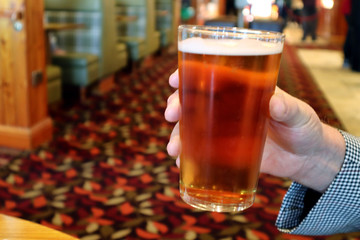 Hand holding a pint of beer in a pub