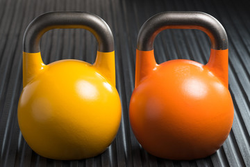 Yellow and orange weight lifting kettlebells inside a gym. Potential copy space on kettlebells.
