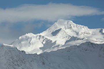 Fototapeta na wymiar Snowy mountains in winter weather with ski slopes