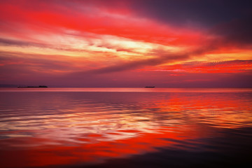 Fiery dramatic landscape with the sea, beautiful sky and ships. Dawn. small waves, almost calm.