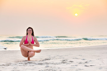 Fototapeta na wymiar Woman practicing yoga on the beach during sunset.