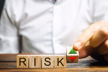 Businessman puts wooden blocks with the word Risk and up and down arrows. Business risk management...