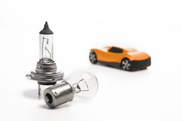 Car light bulb on a white background in front of a yellow car. Car lamps. The concept of service tinning a car.
