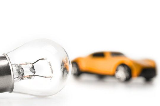 Car light bulb on a white background in front of a yellow car. Car lamp. The concept of service tinning a car.