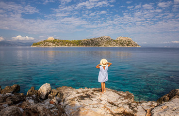 Fototapeta na wymiar Summer morning young woman enjoying beautiful view of the Dorousa island, Aponissos bay-Agistri island, Saronic Gulf, Greece.
